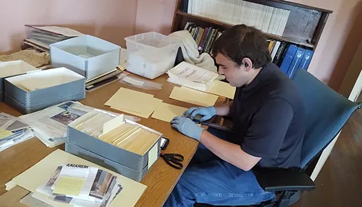 an intern files archive information at a desk in the frank museum